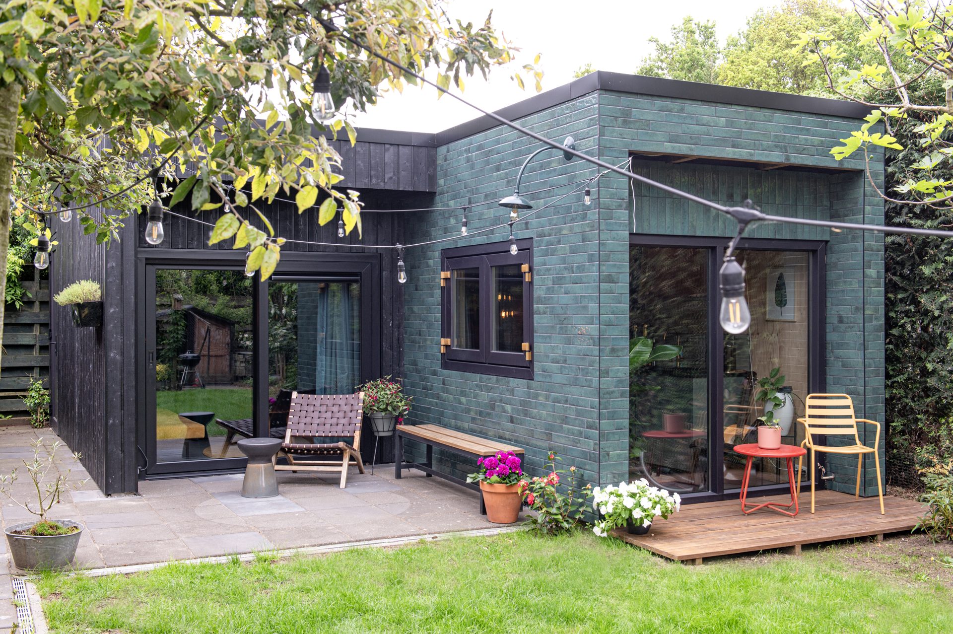 Geluidsstudio met groen geglazuurd metselwerk en terras in de tuin